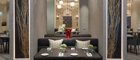 Un comedor moderno con una mesa rectangular, sillas negras y una alfombra estampada.