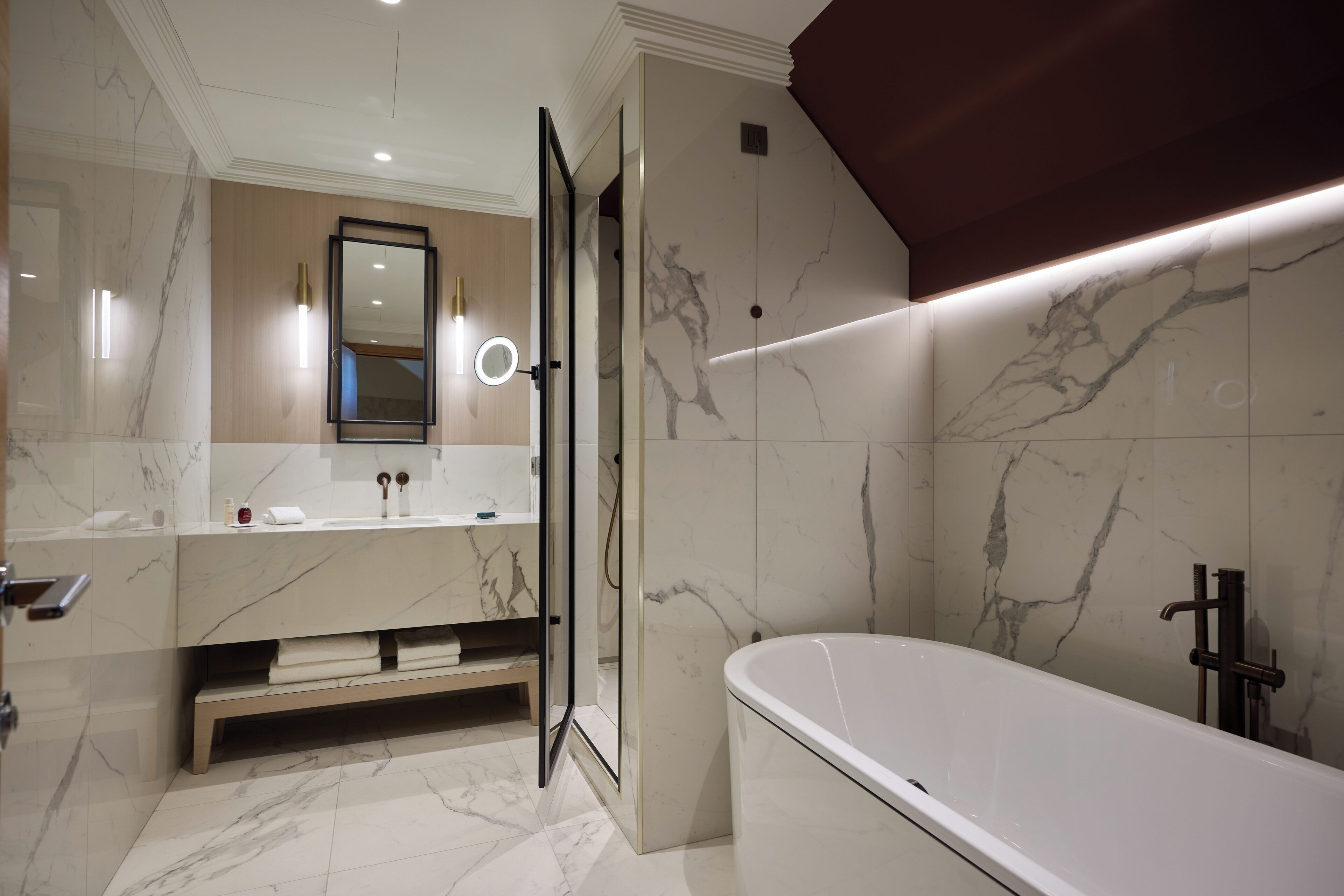 A modern bathroom with a marble floor, a large bathtub, and a glass-enclosed shower.