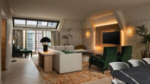 Ein modernes Wohnzimmer mit einer Couch, Sesseln, einem Fernseher und einem Essbereich.