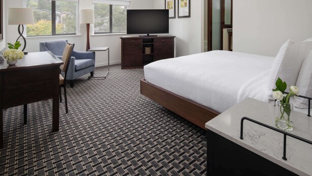 Una habitación de hotel con una cama, un escritorio, una silla, un televisor y una ventana.