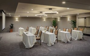 A conference room with multiple tables and chairs, arranged in rows.