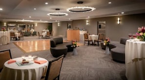 A hotel lobby with round tables, sofas, and a reception area.