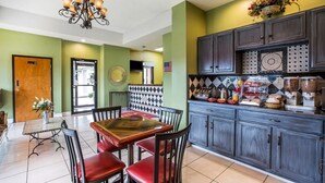 A dining area with a table and chairs, a chandelier, and a kitchen area with cabinets and a countertop. - Budgetel Inn & Suites (Augusta)