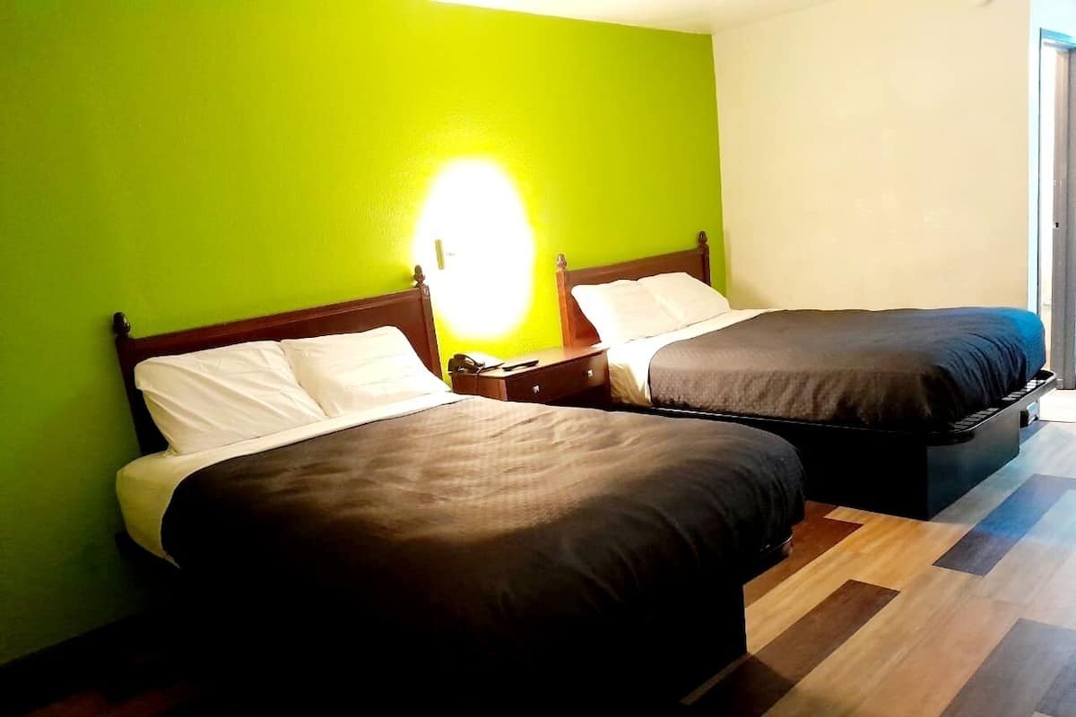 A room with two beds, a wooden headboard, and a green wall.