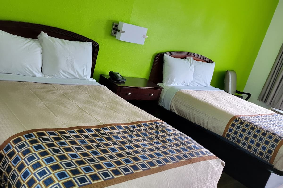 A hotel room with two beds, green walls, and a wooden floor.