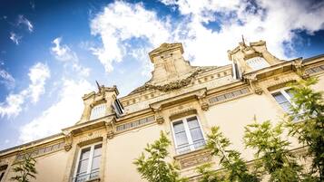 Un edificio histórico con detalles arquitectónicos ornamentales, que incluyen un balcón y molduras decorativas.