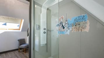 Un baño moderno con cabina de ducha de vidrio, tragaluz y un adhesivo decorativo en la pared.