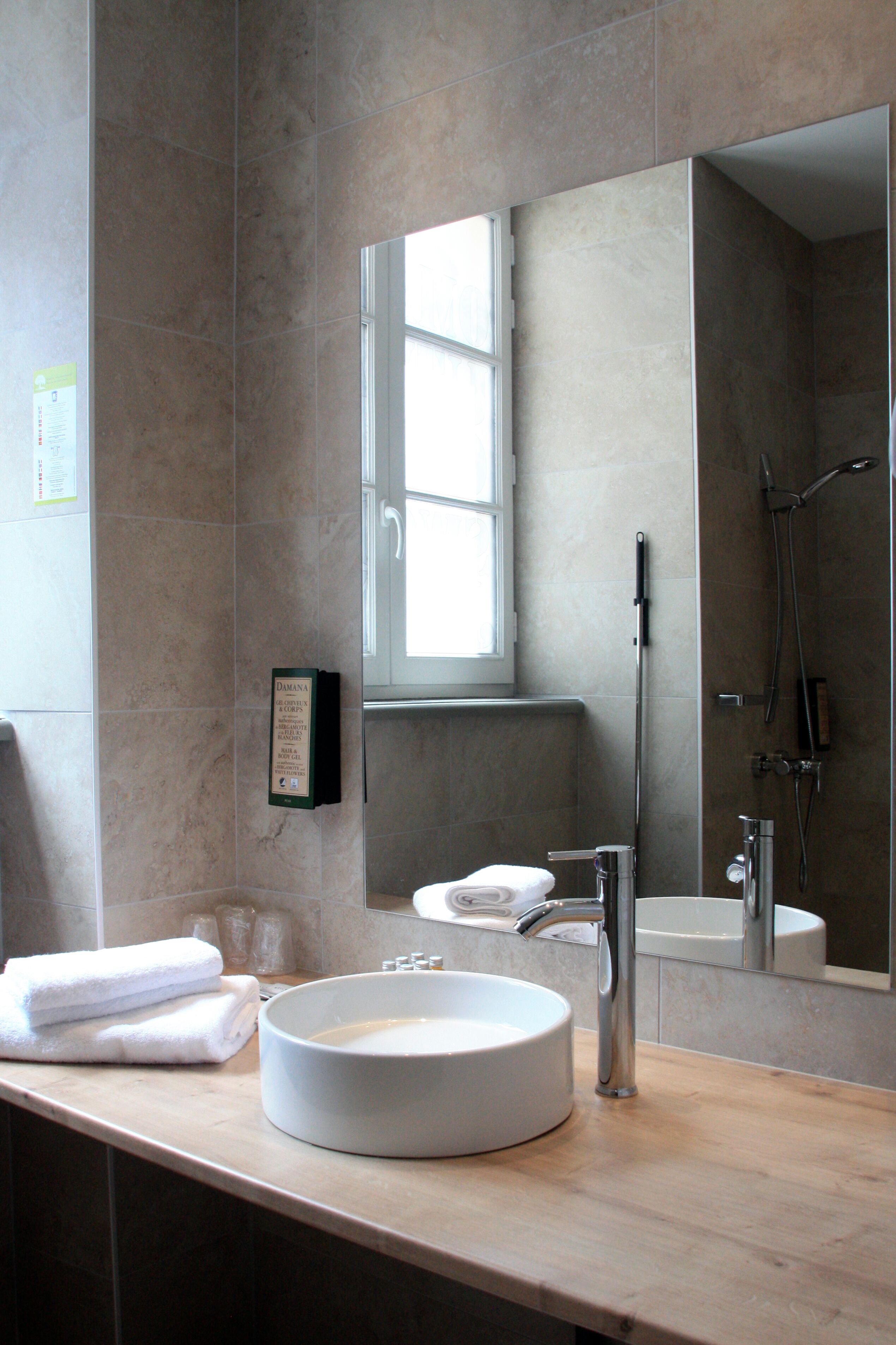 Un baño moderno con un lavabo redondo, un espejo y una zona de ducha.