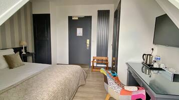 Una habitación de hotel con una cama, un escritorio, una silla, un televisor y una puerta.
