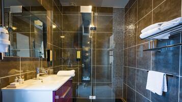 A modern bathroom with a glass-enclosed shower, a vanity with a sink, and a towel rack.