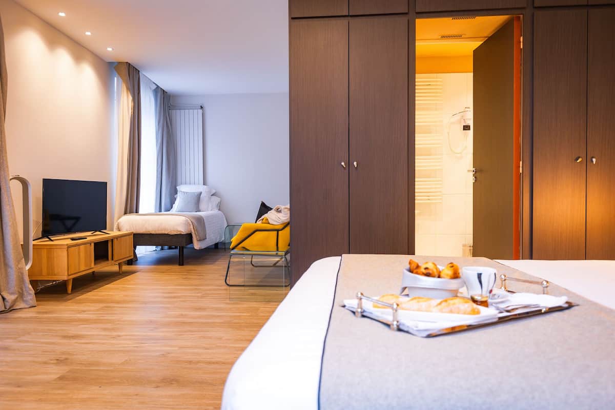 Une chambre d’hôtel avec un lit, une télévision, un bureau et une salle de bain visible à travers une porte ouverte.
