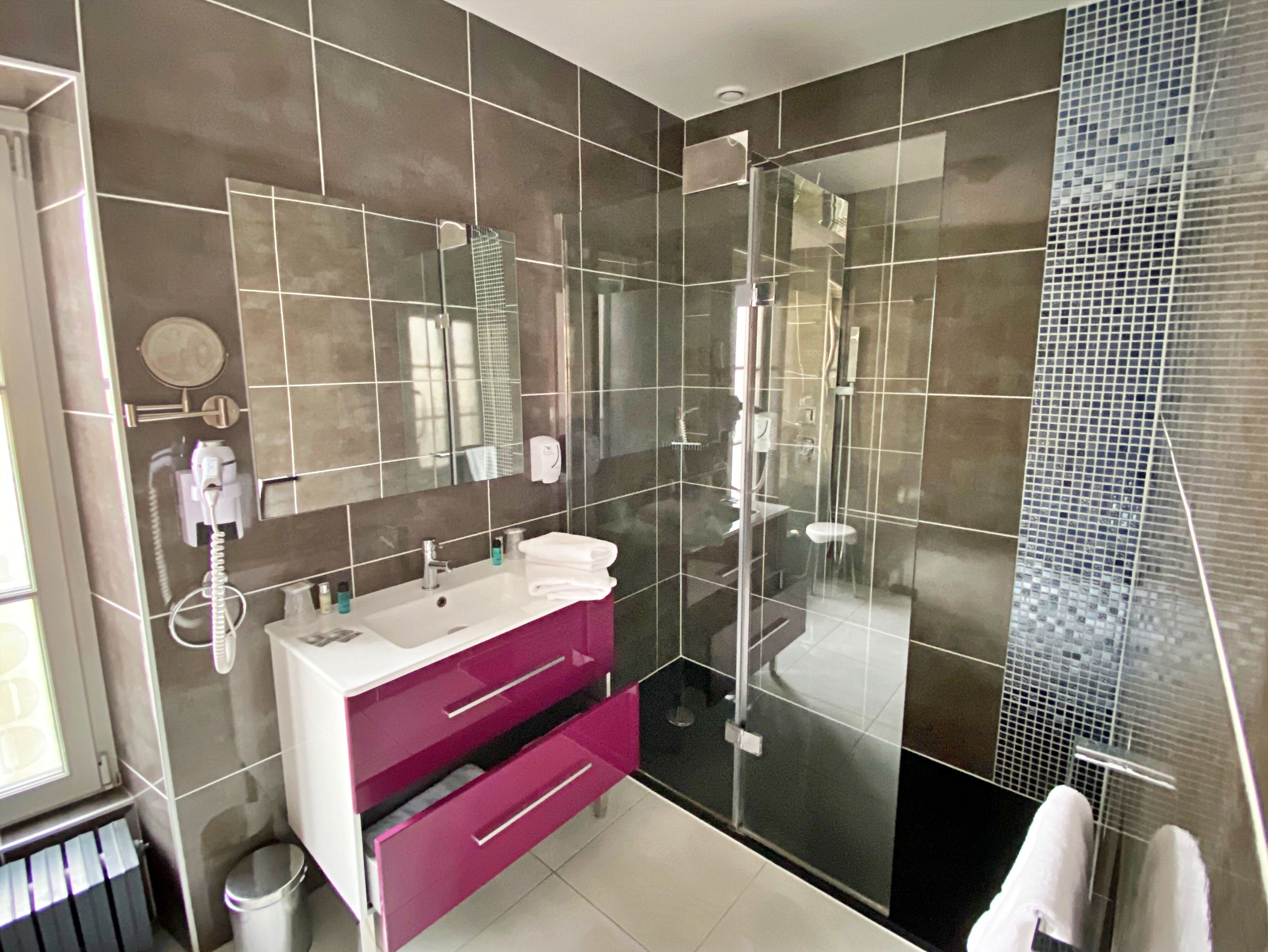 Un baño moderno con ducha envuelta en vidrio, tocador con espejo y un inodoro.