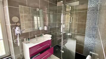 Un baño moderno con ducha envuelta en vidrio, tocador con espejo y un inodoro.