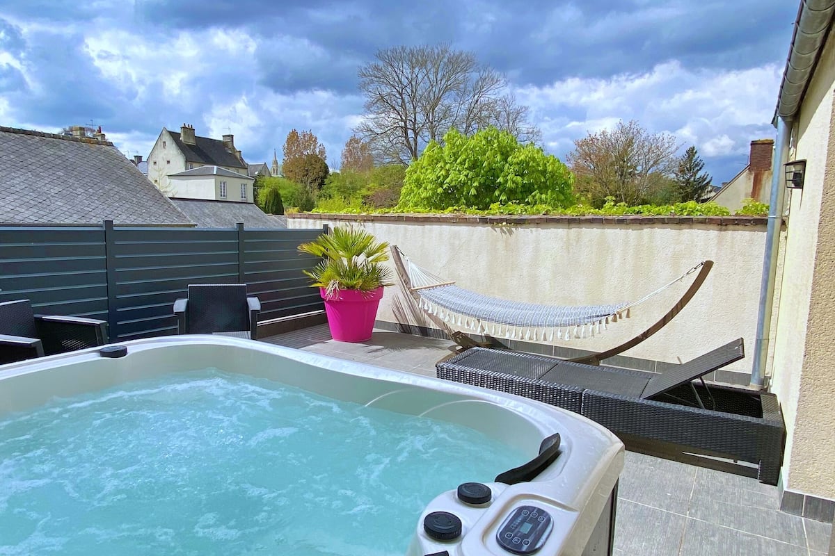 Un bain à remous sur une terrasse sur le toit, offrant une vue sur les bâtiments et les arbres environnants.