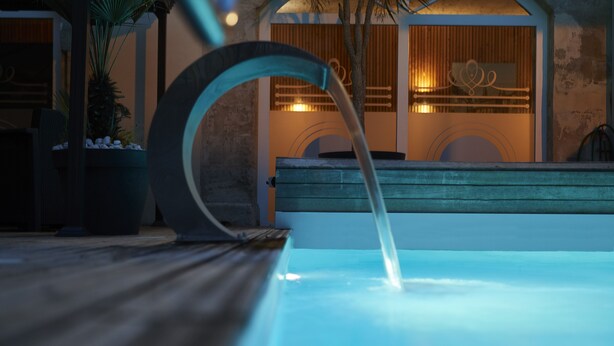 A pool with a curved edge and a water feature.