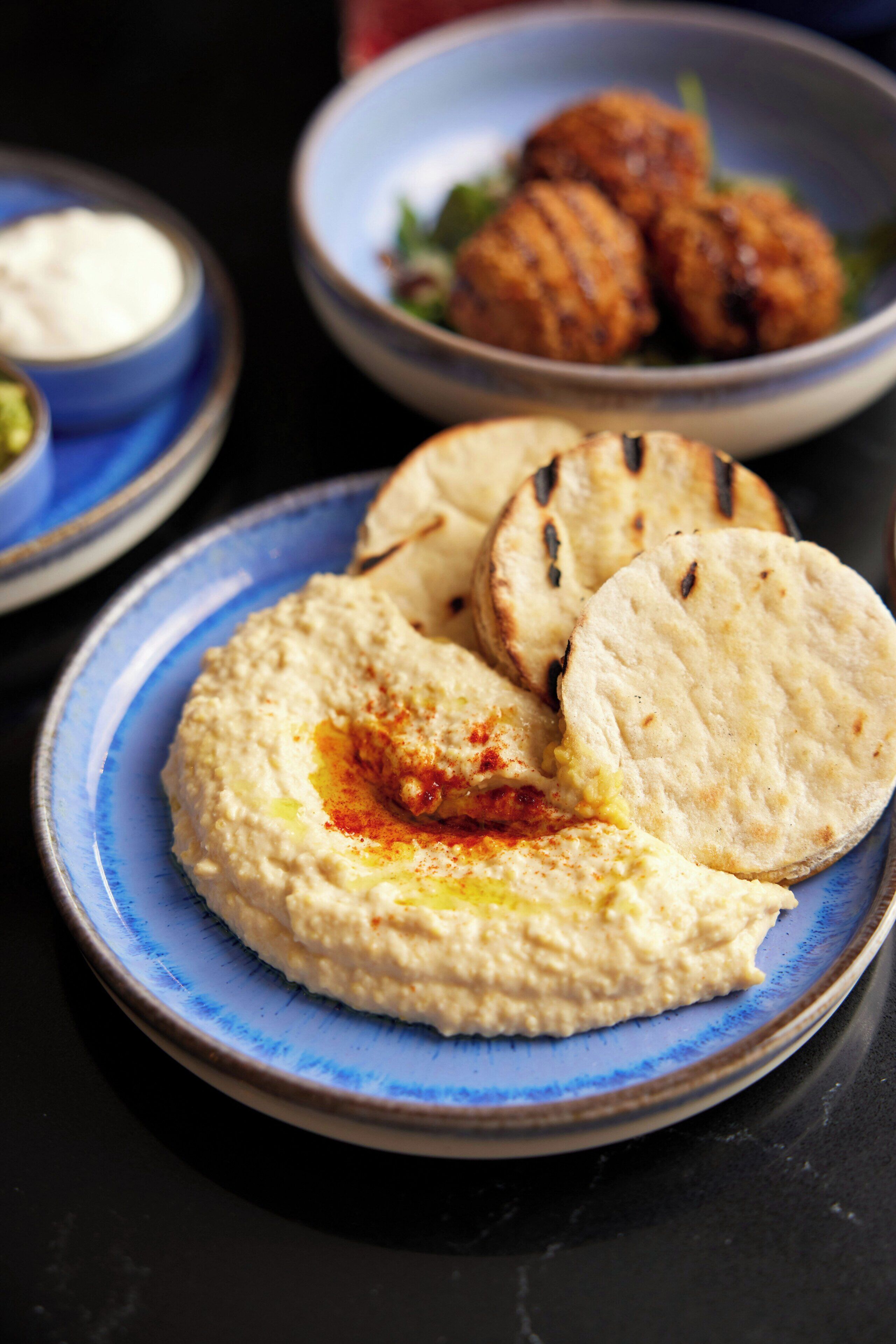 A plate of hummus with pita bread and a bowl of falafel.