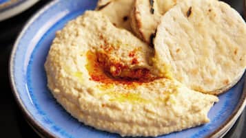 A plate of hummus with pita bread and a bowl of falafel.