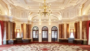 A grand hall with a large chandelier, ornate ceiling, and red carpet. - The Clermont London, Charing Cross (London)