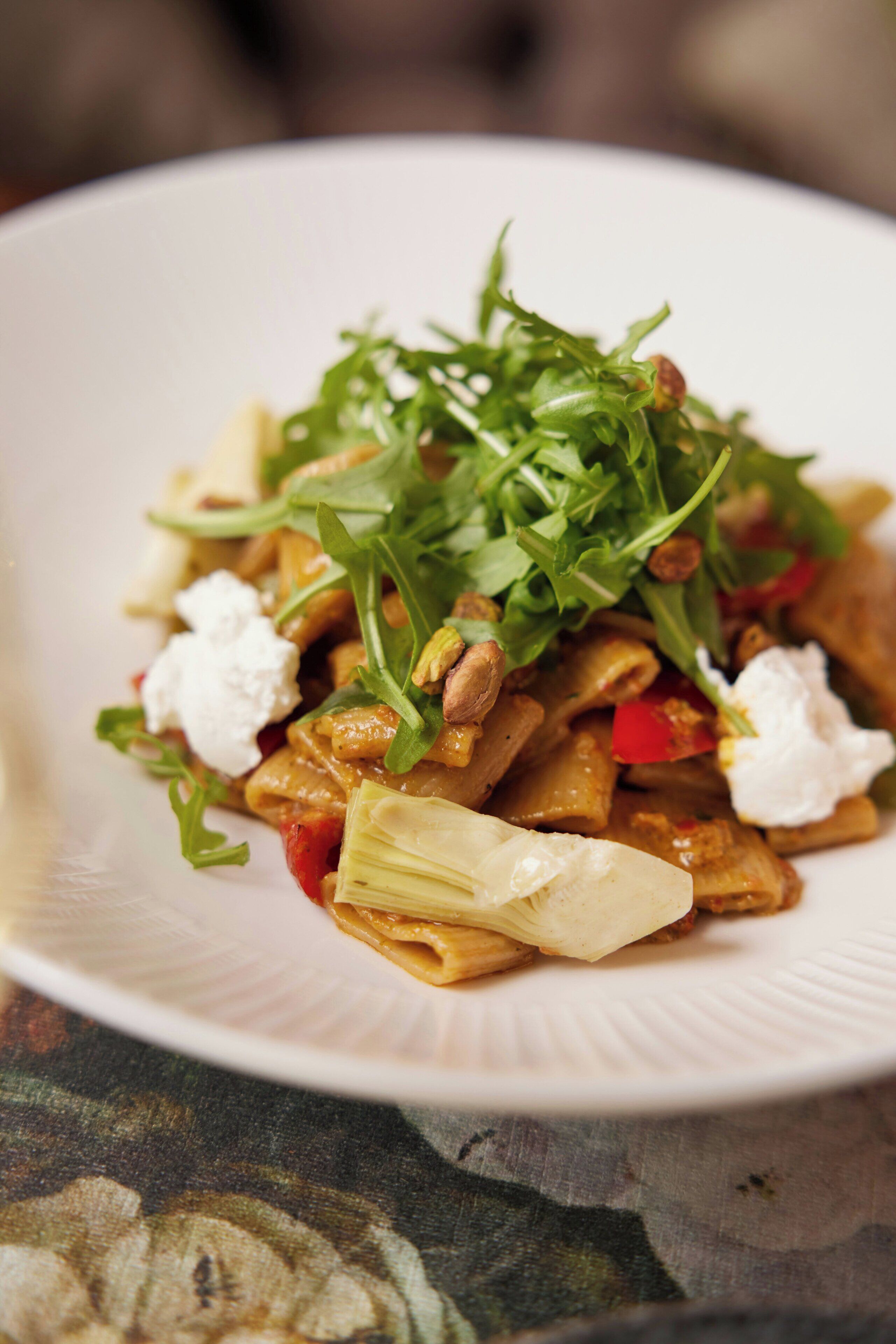 A plate of pasta with greens and cheese.