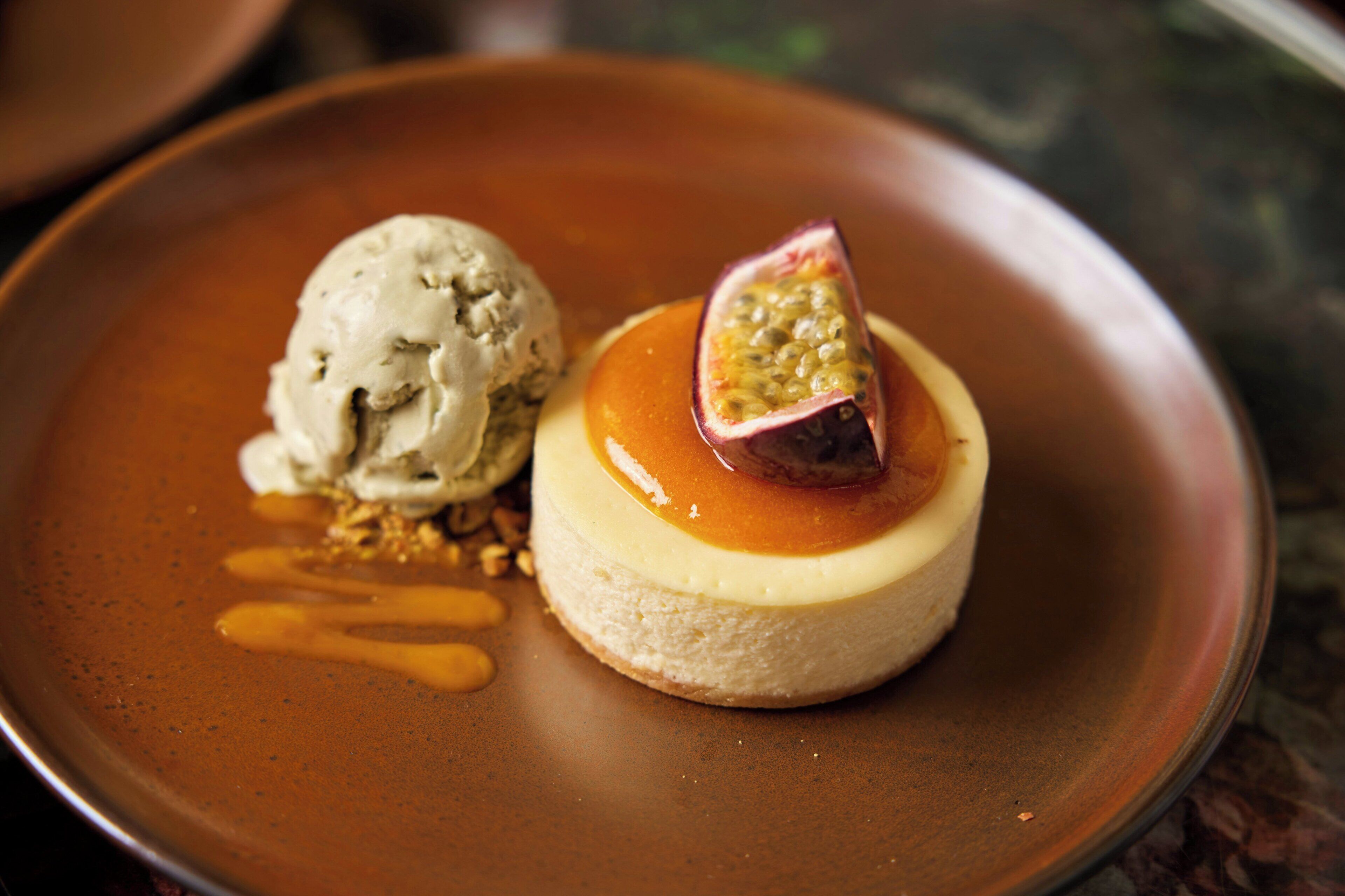 Un dessert servi dans une assiette, composé d’une boule de glace et d’une garniture de fruits.