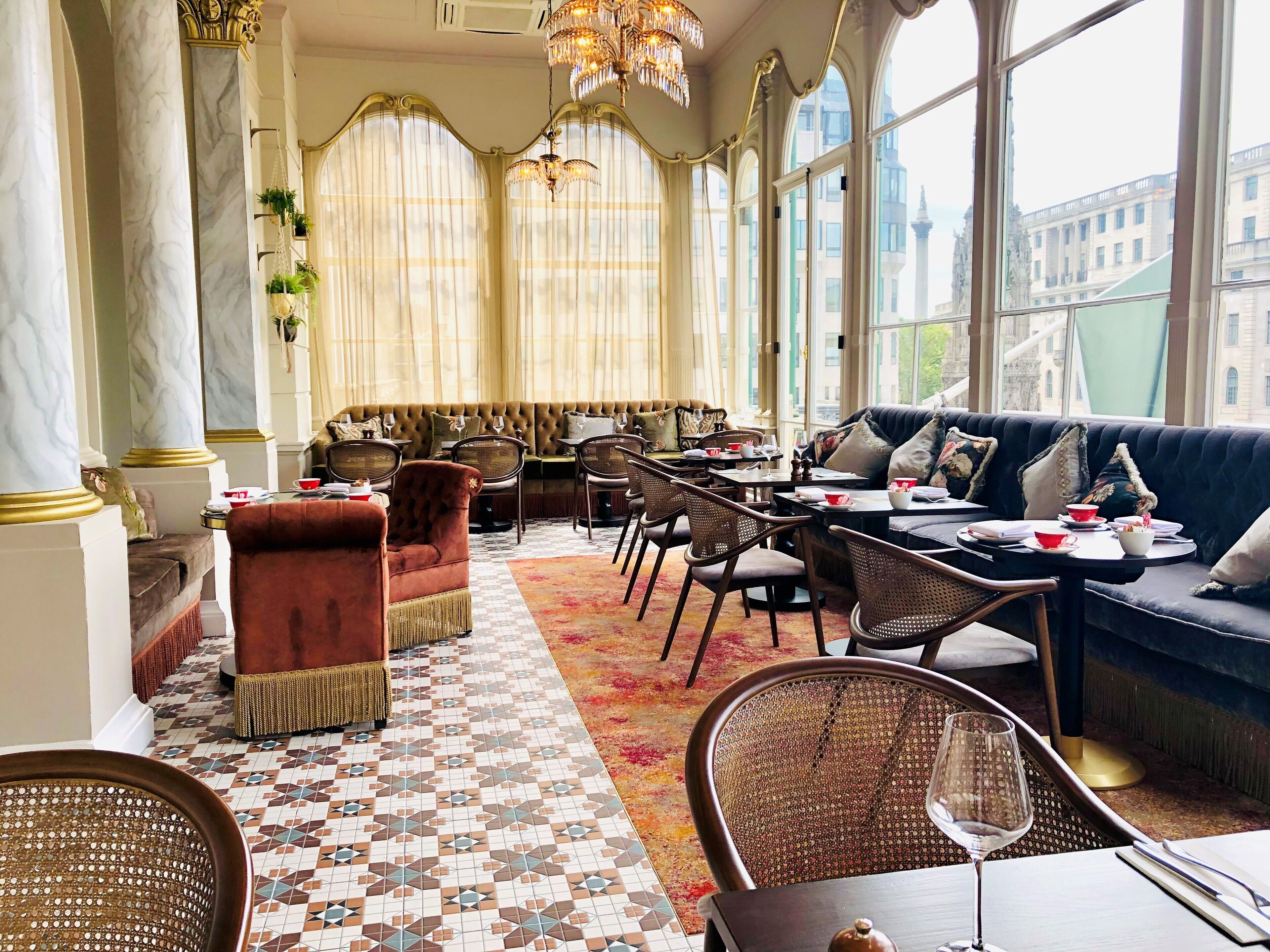 A spacious lounge with a checkered floor, a sofa set, and a dining area with chairs and tables.