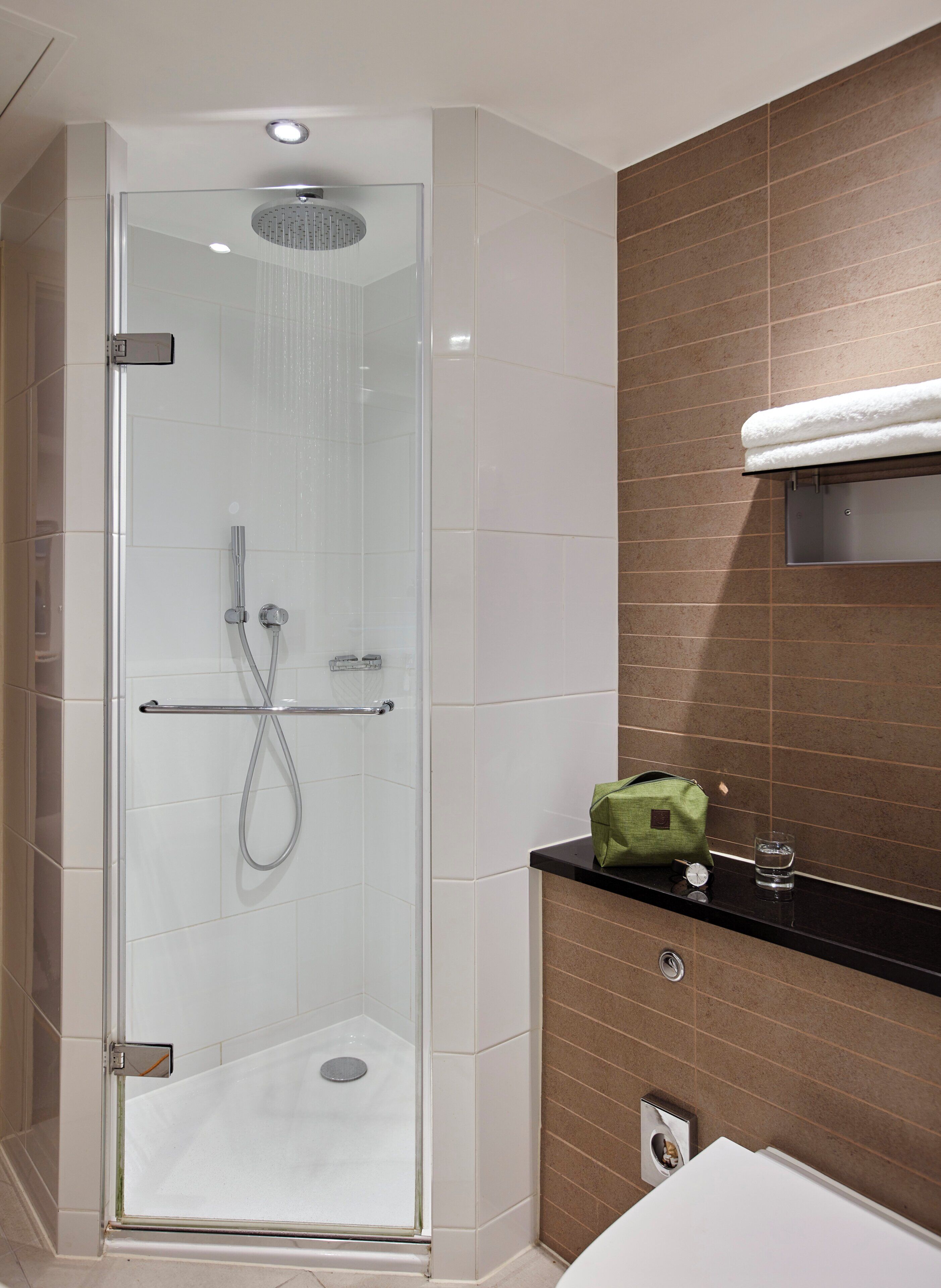A modern bathroom with a glass-enclosed shower, a vanity with a mirror, and a towel rack.