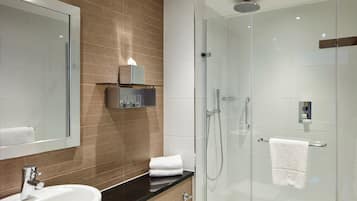 A modern bathroom with a glass-enclosed shower, a sink, and a mirror.