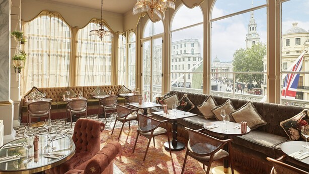 A luxurious interior with a large window, elegant furniture, and a chandelier. - The Clermont London, Charing Cross (London)