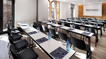 A conference room with multiple tables, chairs, water bottles, and a presentation screen.