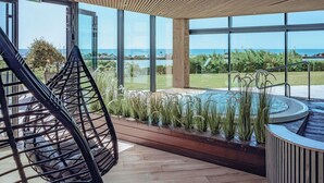 A modern indoor pool area with a view of the sea, a wooden ceiling, and a hanging chair. - Côte Ouest Thalasso & Spa Les Sables d'Olonne - MGallery Collection (Les Sables-d'Olonne)
