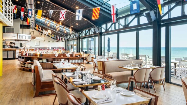 A restaurant with a high ceiling, large windows, and a view of the sea. - Côte Ouest Thalasso & Spa Les Sables d'Olonne - MGallery Collection (Les Sables-d'Olonne)