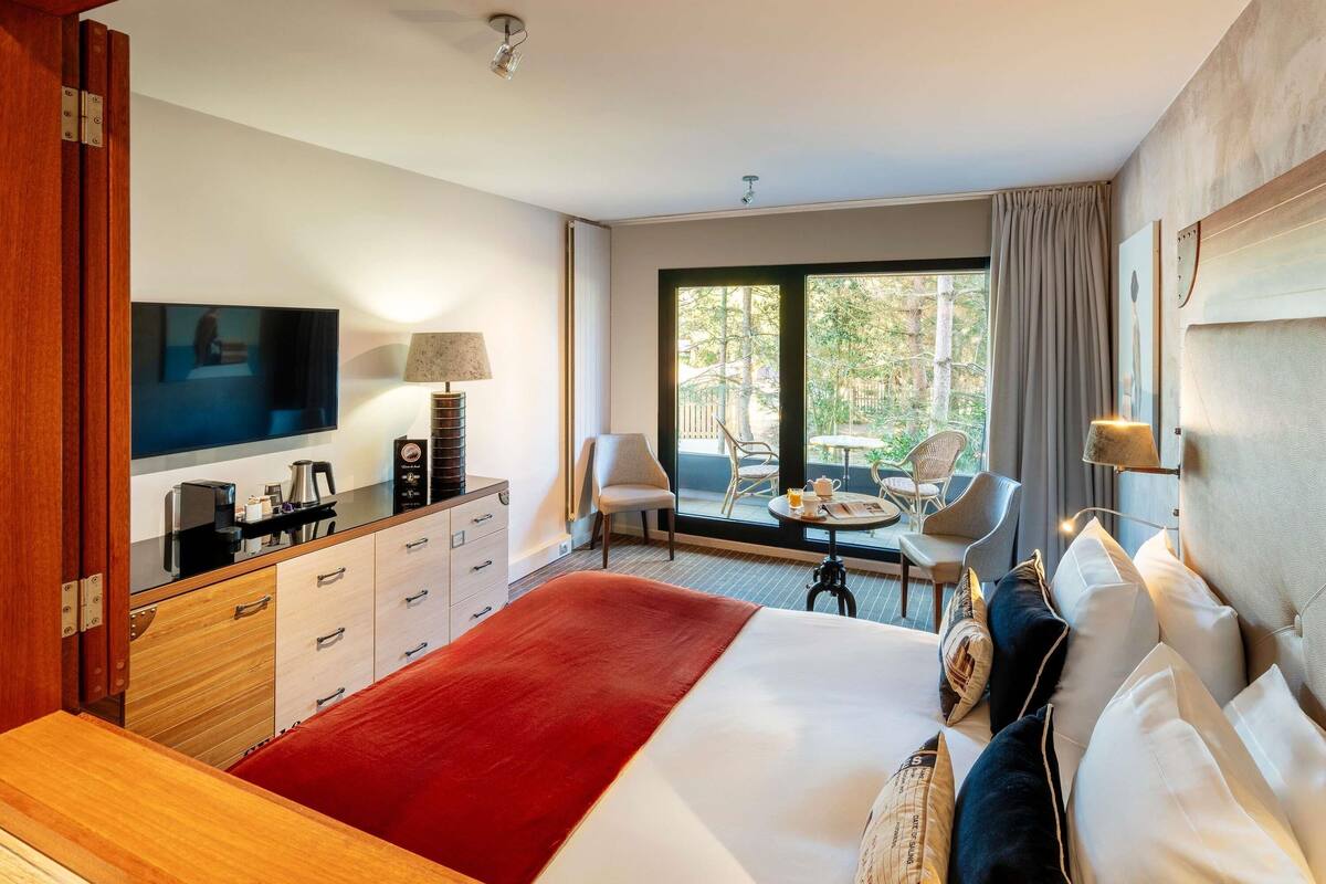 Une chambre d’hôtel équipée d’un lit, d’une télévision, d’un bureau avec une lampe, d’une chaise et offrant une vue sur l’extérieur.