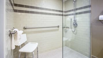 Un bagno con doccia, barra di sostegno, lavandino bianco e portasciugamani.