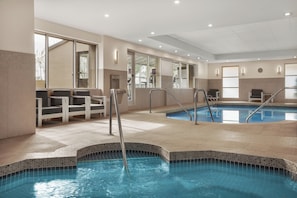 An indoor swimming pool with clear water, tiled steps, and seating areas. - Holiday Inn Calgary-Airport by IHG (Calgary)