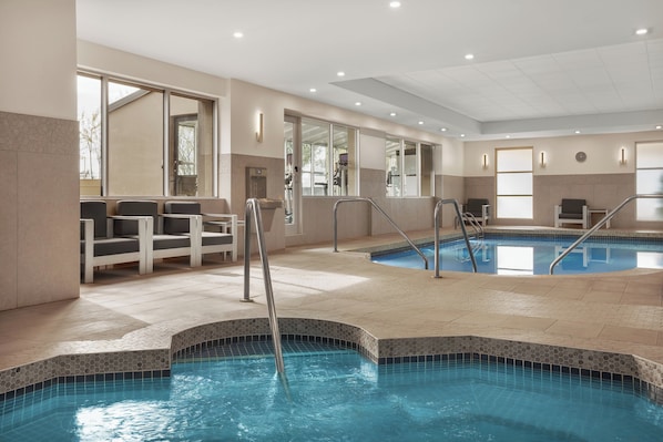 An indoor swimming pool with clear water, tiled steps, and seating areas.