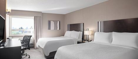 A hotel room with two beds, a desk, a chair, and a TV.