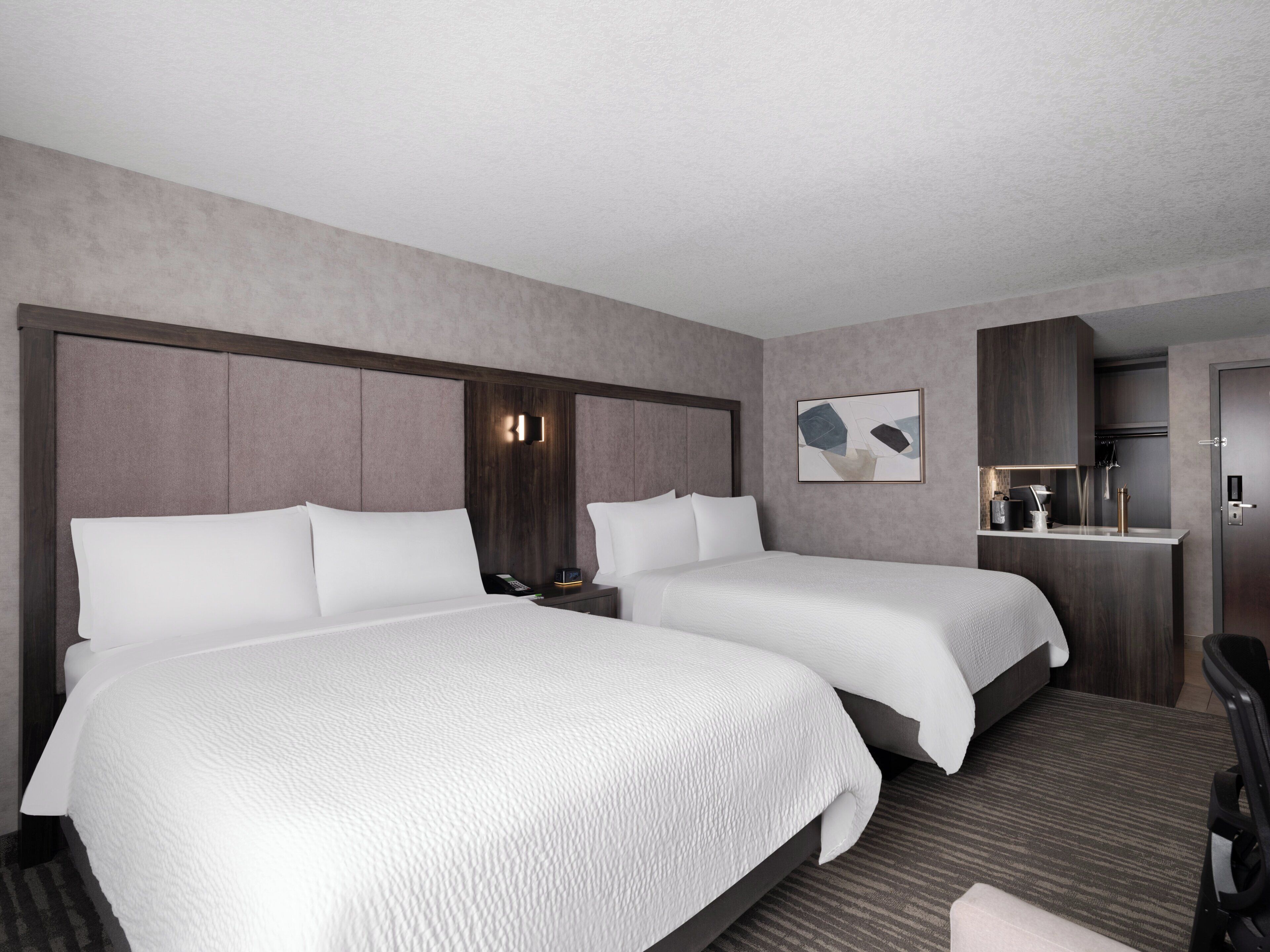 Ein Hotelzimmer mit zwei Betten, einer kleinen Küchenzeile und einer Sitzecke.