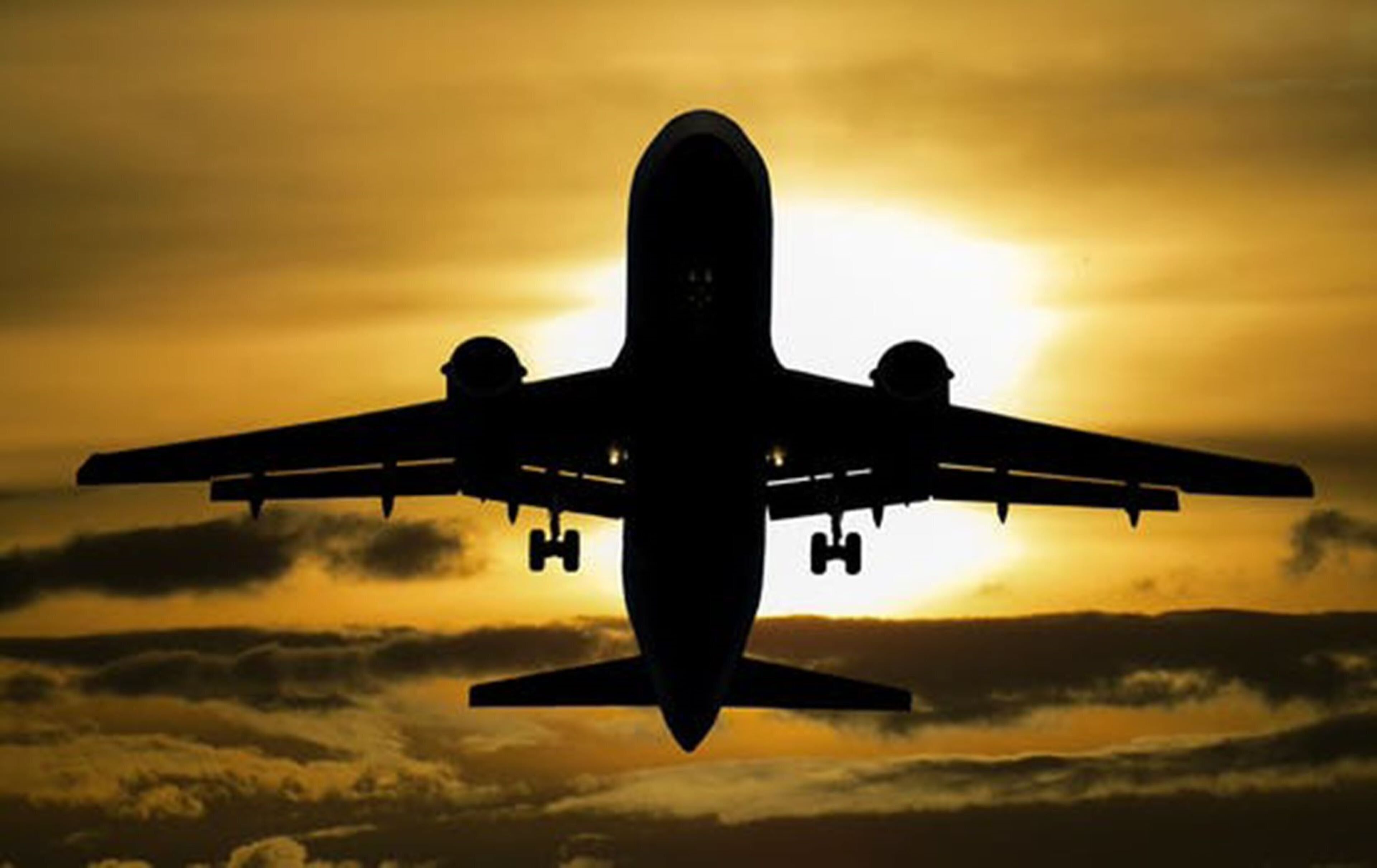 Silhueta de avião contra um pôr do sol.