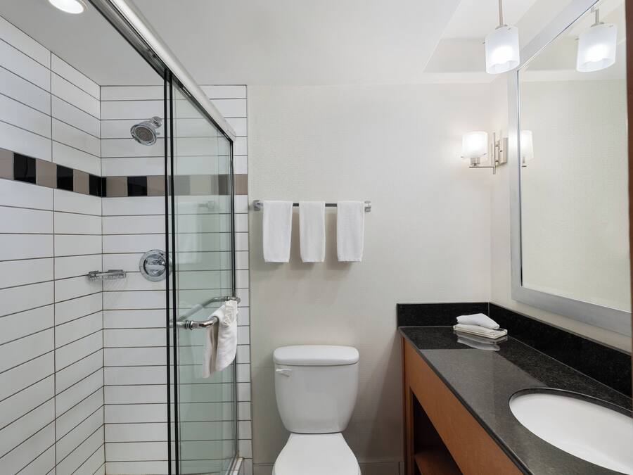Un bagno moderno con cabina doccia in vetro, un WC bianco e un lavabo su piano nero.