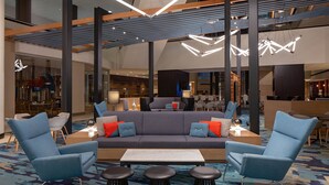 A modern lobby with a central seating area, high ceilings, and contemporary lighting fixtures.