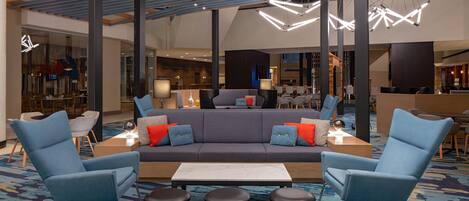 A modern lobby with a central seating area, high ceilings, and contemporary lighting fixtures.