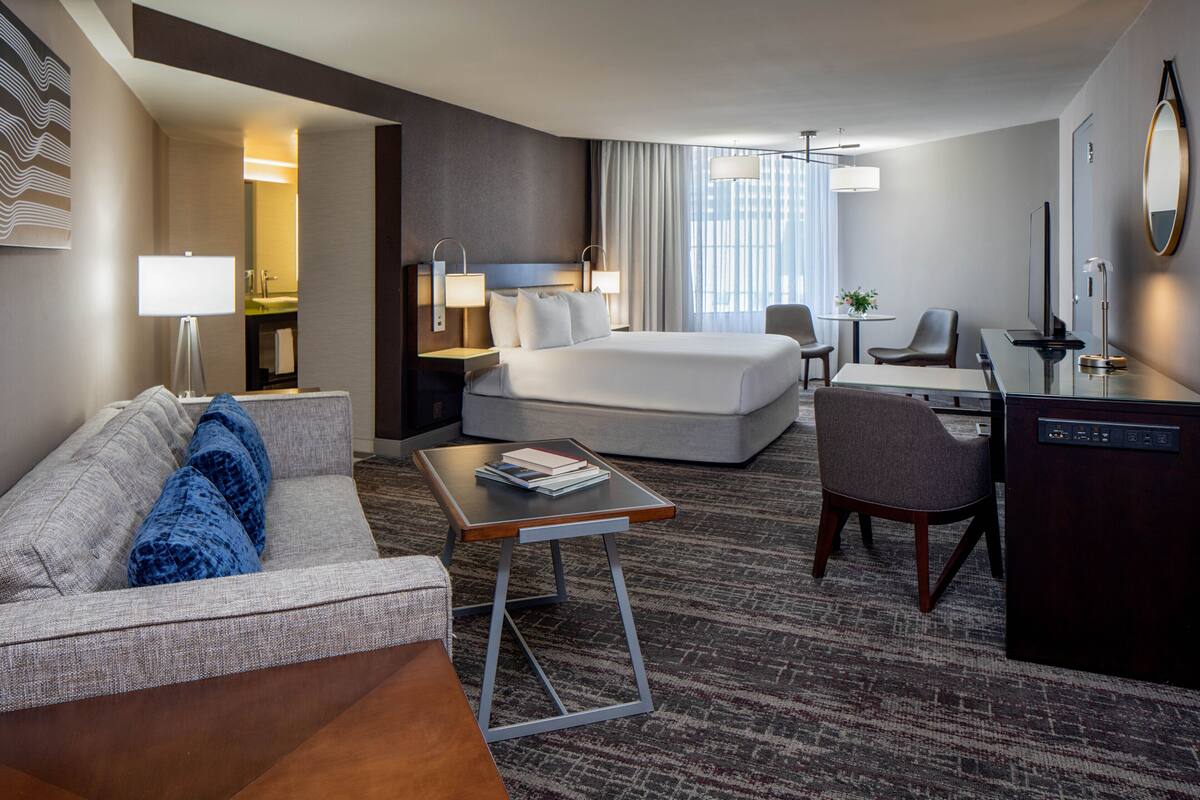 Une chambre d’hôtel comprenant un lit, un bureau, une chaise, un canapé et une petite table.