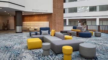 A modern lounge with sofas, ottomans, and a patterned carpet.