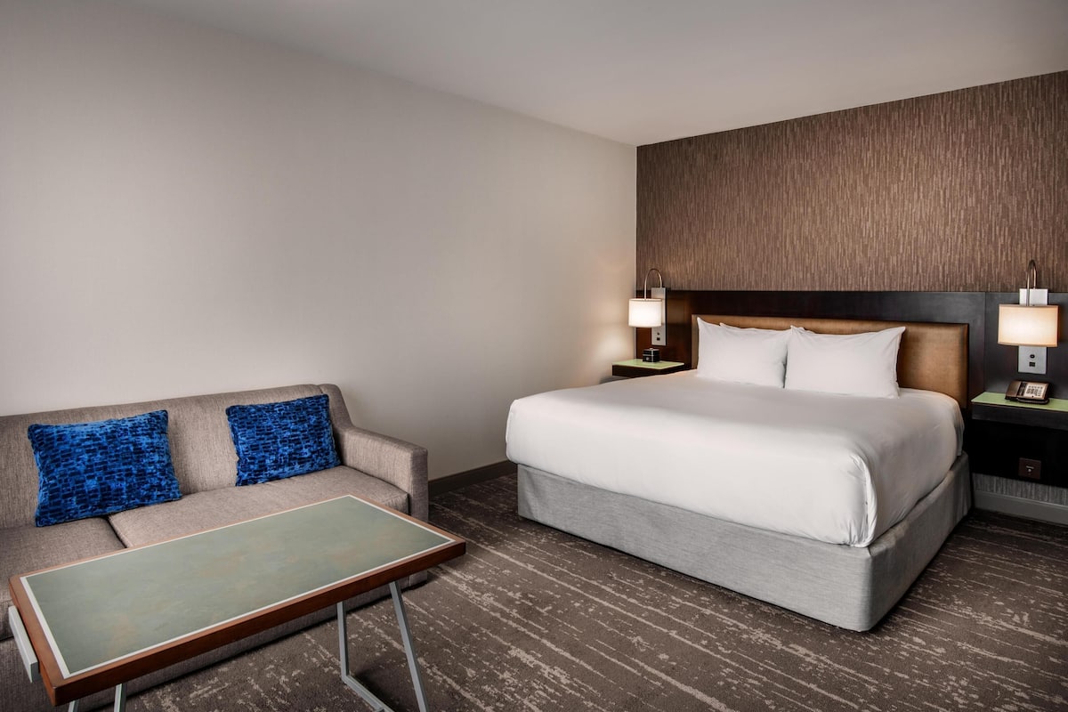 Une chambre d’hôtel comprenant un lit, un canapé, une petite table et deux tables de chevet avec des lampes.