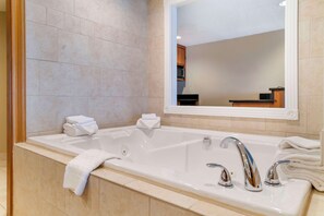 A modern bathroom with a large bathtub, two faucets, and a mirror.