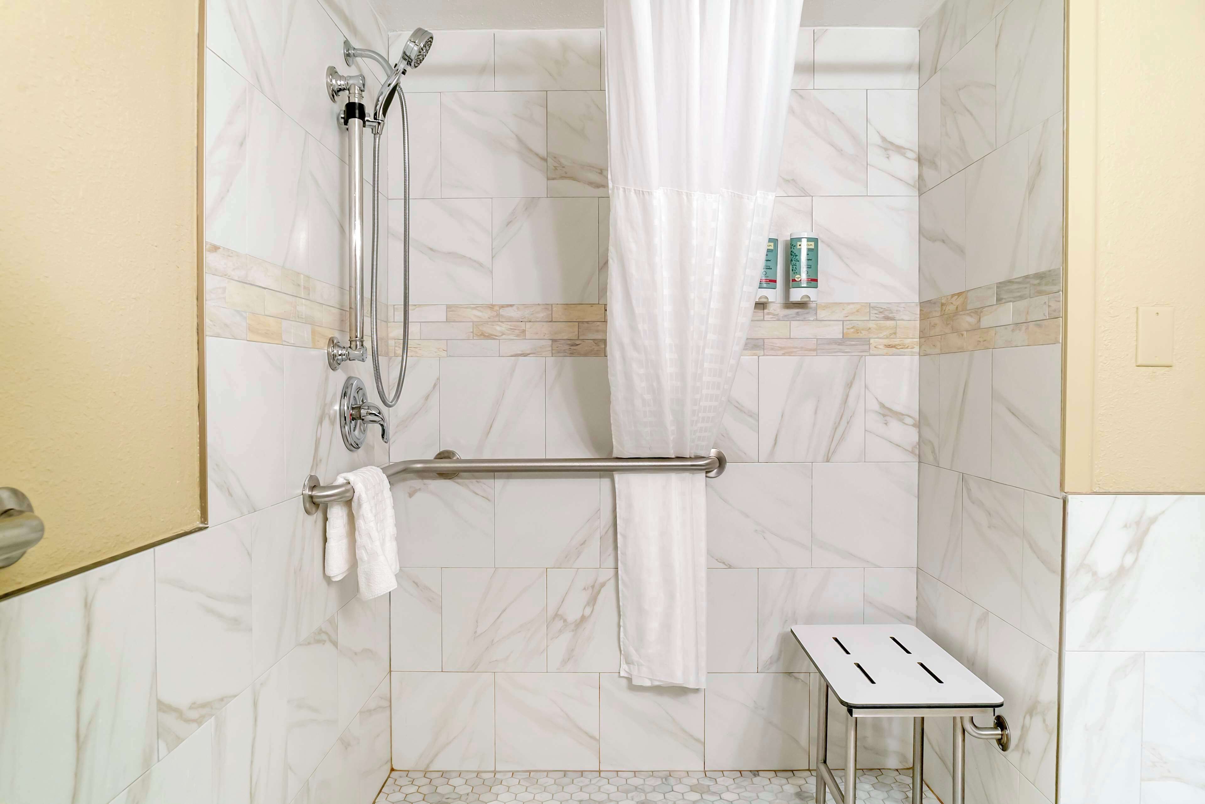A shower area with a glass door, a towel rack, and a small step stool.