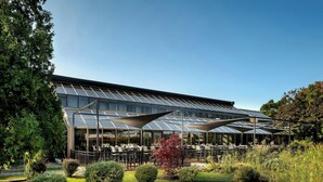 Een modern gebouw met een glazen gevel en een terras.