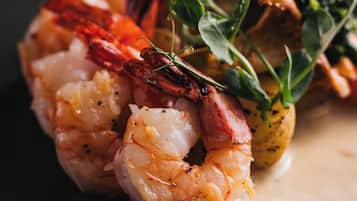A close-up of a dish with shrimp, greens, and a creamy sauce on a dark plate.