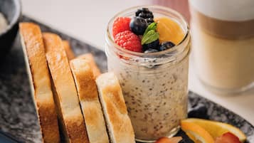 A breakfast setting with a glass of milk, a jar of fruit salad, and slices of toast on a plate.