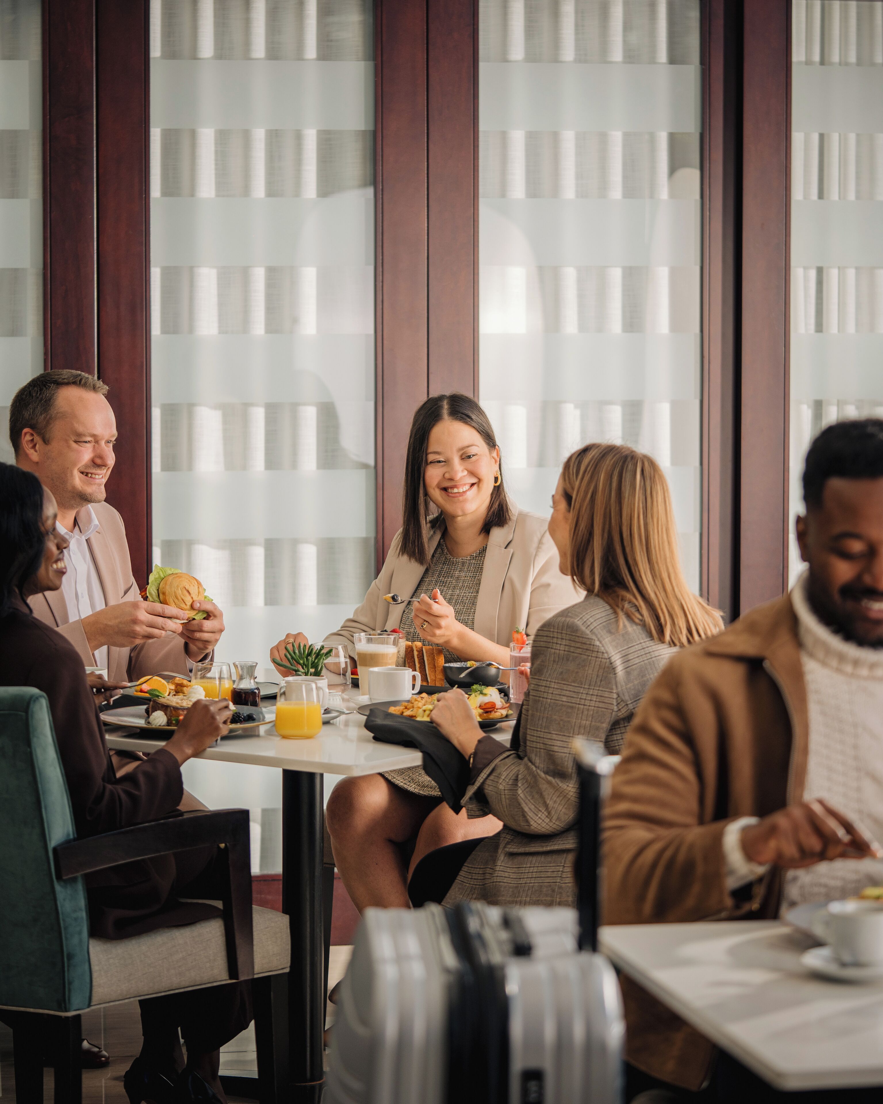 Un grupo de personas cenando en un restaurante moderno con ventanas amplias y un interior limpio y minimalista.